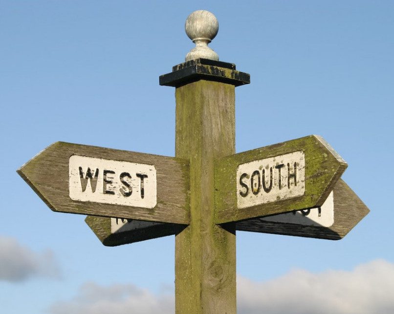 Wooden signpost with West and South arrows.