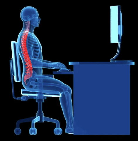 A man sitting at his computer desk with the back of his neck and shoulder pain.